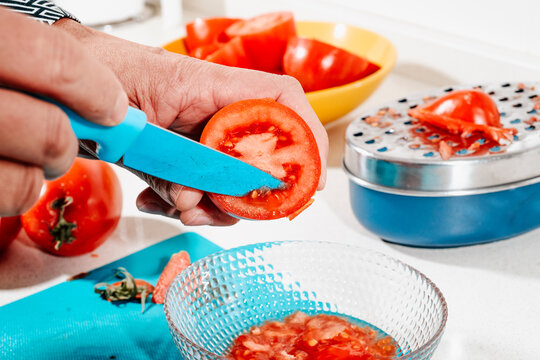 a man removes the seeds from a halved tomato