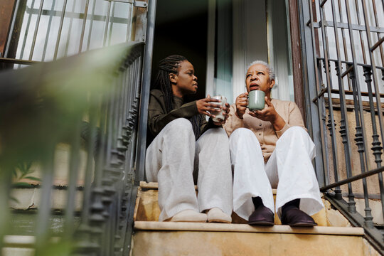 Mother and daughter sharing coffee and conversation on stairs