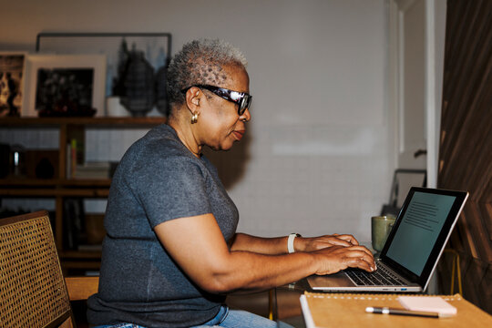 Senior woman typing on laptop working at home ugc
