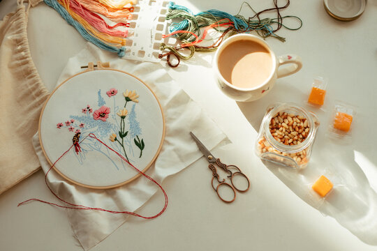 Still life with flowers embroidery and a cup of coffee at the table.