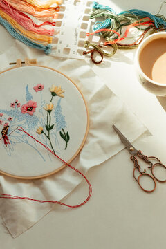 Still life with flowers embroidery and a cup of coffee at the table.