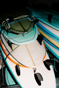 Flash-lit medium shot of several surfboards stacked and tied