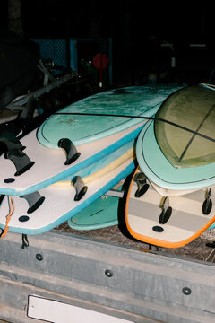 Multiple surfboards stacked and secured on a wooden base at night