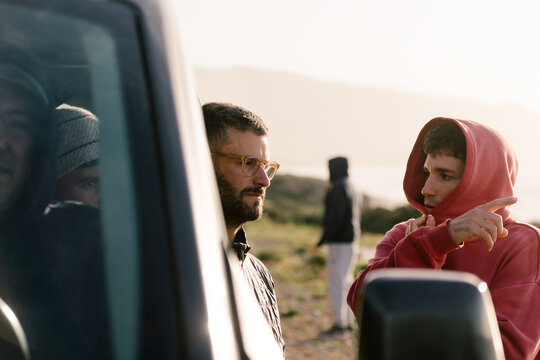 Friends chatting next to a van during a stop on a road trip in Morocco