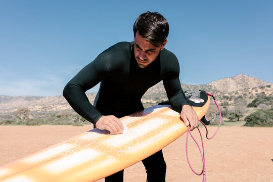 A surfer waxing his board getting ready for a day of practice
