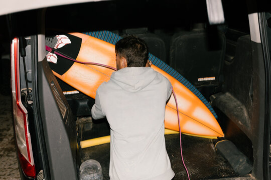 Man arranging several surfboards in the back of a van