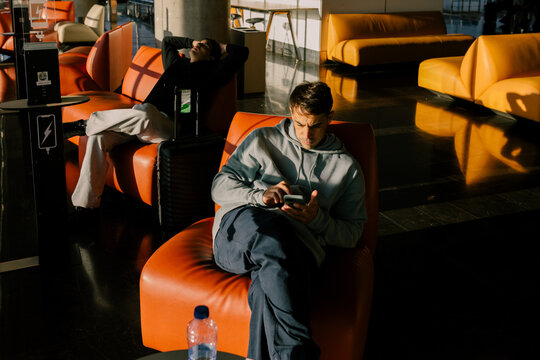 Friends sitting at an airport in Morocco using their cell phones