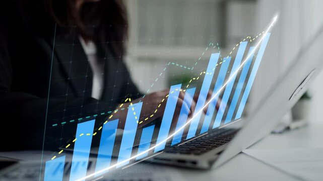 A businesswoman focuses on financial data displayed on a laptop, showcasing rising graphs and bar charts, representing growth and success in a modern office setting. Copula