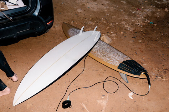 Medium shot lit by flash of two surfboards placed on the dirt floor
