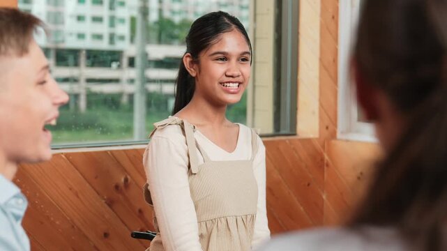 Young student smiling while listening other student in meeting or group discussion. Cute teenager talking about her experience and sharing to friends in mixed races. Creative education. Edification