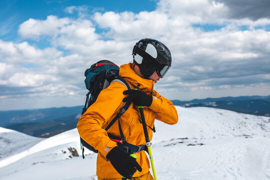 Man in an orange jacket prepare to ride in winter mountains.