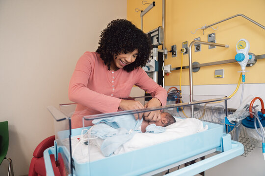 Mother dressing newborn baby in hospital nursery