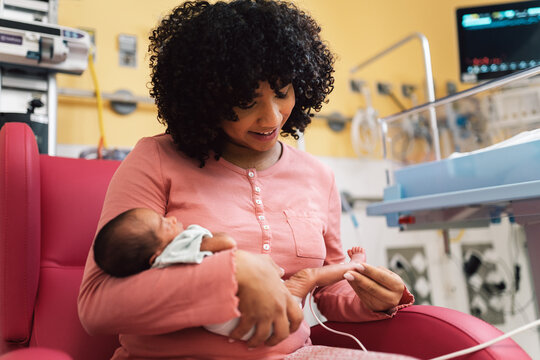 Mother holding newborn baby in hospital nicu