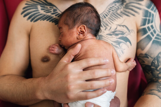 Father holding newborn baby skin to skin