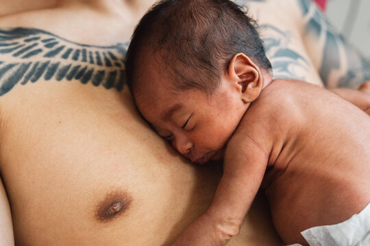 Newborn baby sleeping skin-to-skin with father