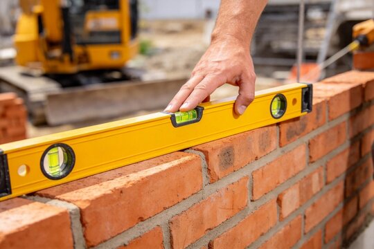 Hand using level tool on brick wall