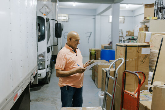 Warehouse Worker Checks Inventory of Boxes in a Storage Area
