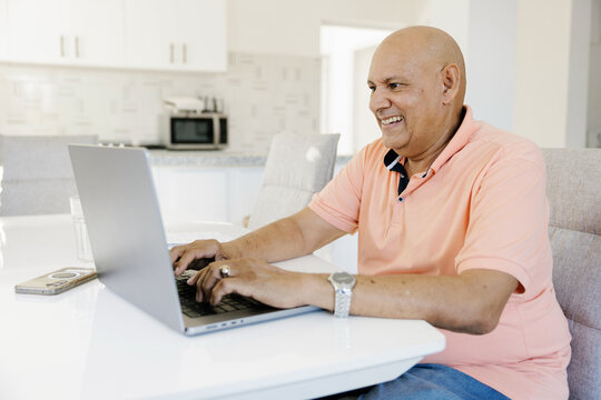 Older Man Works on Laptop at Home During Daytime