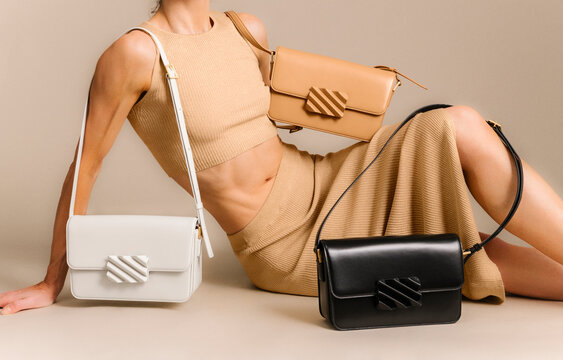 Fashion Model With Three Handbags In Beige Studio