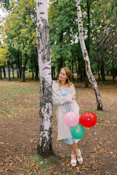 Woman Holding Balloons in Park During Daytime With Trees Around