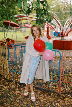 Woman Holding Balloons at Amusement Park in Autumn