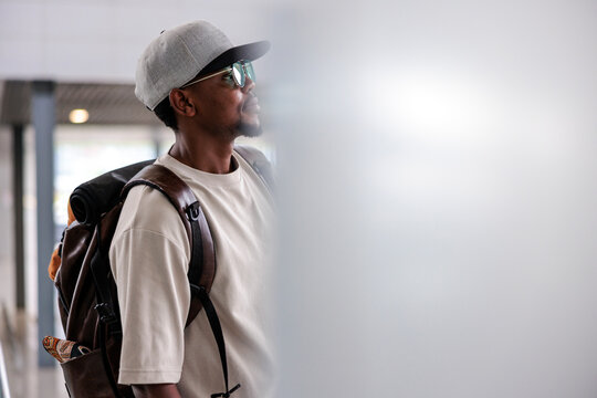 Man with backpack and cap looking towards the light.