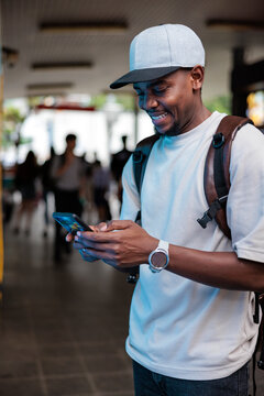 Smiling man checks phone in public space.