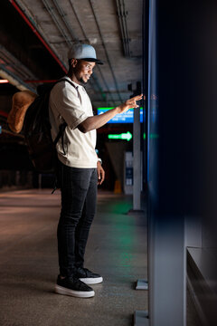 Man uses touch screen kiosk in modern transit station.