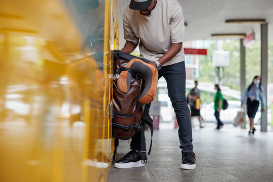 Man packing backpack in train station locker.