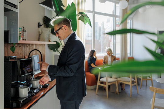 Business professional choosing coffee from machine in office