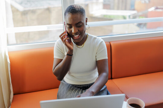 Woman telecommunicating and working on laptop at bright office