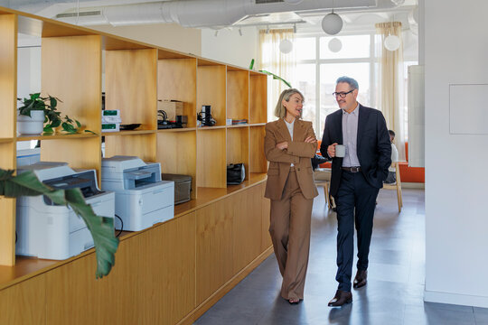 Business colleagues walking and conversing in modern office
