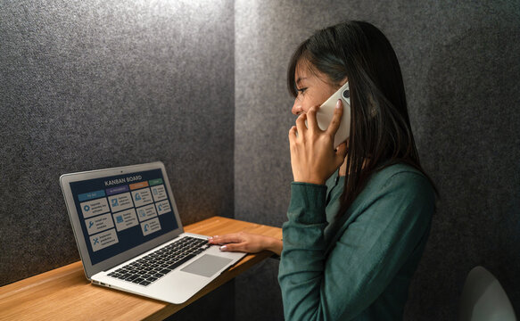 Woman using laptop and phone in private workspace