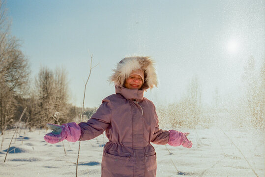Smiling Child Playing with Snow on Sunny Winter Day