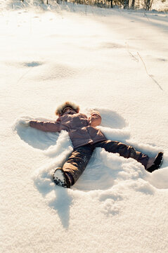 Child Making Snow Angel in Bright Winter Field