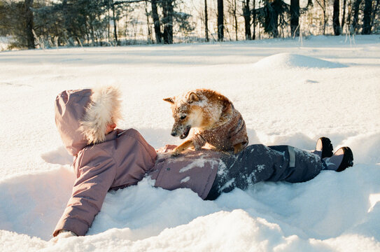 Child Playing with Dog in Snowy Winter Field