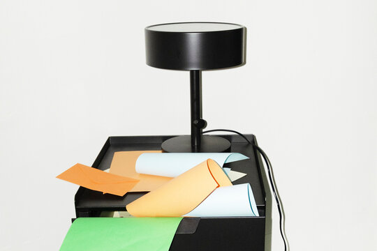 View of office desk with lamp, colourful papers and office tools 