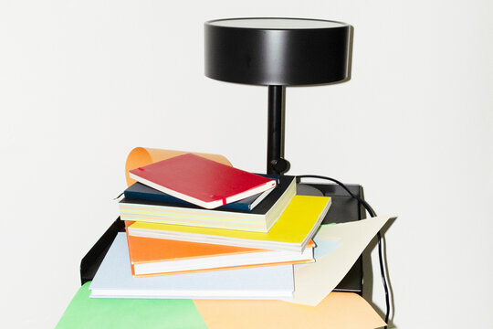 View of office desk with lamp, colourful papers and office tools 