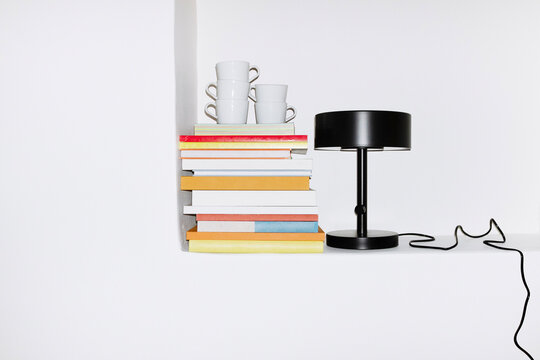 Pile of colourful paper books and black minimal lamp with wire