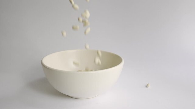 White_beans_pouring_into_white_bowl_white_background_4k_10bit_120fps