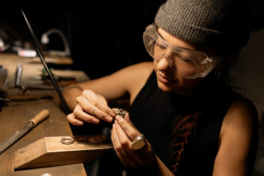Goldsmith shaping metal with coping saw
