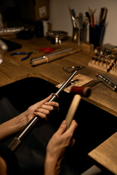 A jeweler taps a ring with a hammer