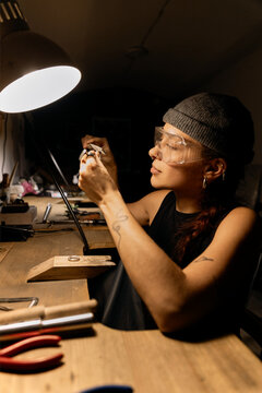 Goldsmith shaping metal with coping saw
