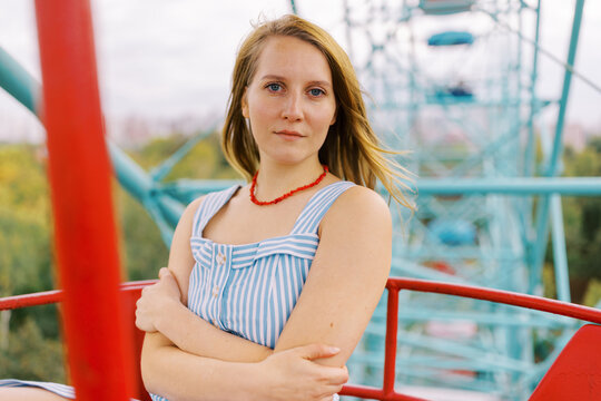 Young Woman Sits in a Ferris Wheel Cabin on a Cloudy Day