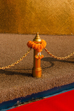 Flowers decorate a post at a ceremonial event near a golden backdrop 