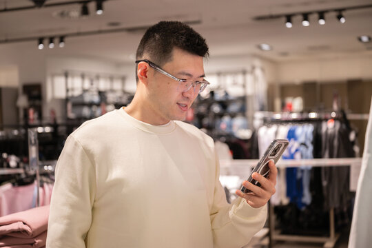 Chinese Man Shopping in Store While Using Smartphone for Assistance