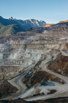 Open pit quarry landscape against mountain backdrop