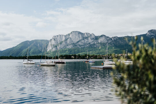 Sailboats anchored on a lake with alpine mountains in background