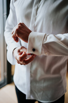 Close-up of groom fastening cufflink