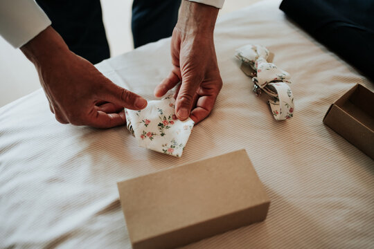 Groom folding floral pocket square on wedding morning